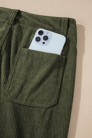 Olive corduroy flared leg trousers with a phone in the pocket.