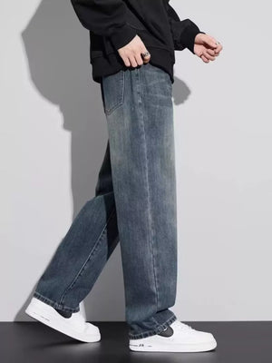 Men's vintage wash relaxed fit jeans in blue cotton, shown with a black hoodie and white sneakers.