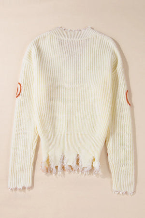 Beige distressed knit sweater with orange pumpkin patches on sleeves and frayed hem.