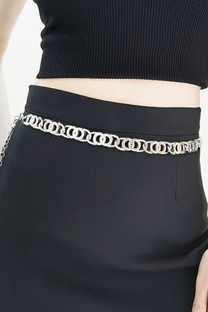 Silver chain belt with interlocking circle links worn at the waist over a black skirt.