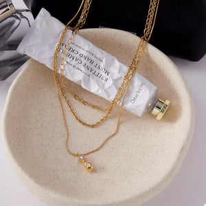 Elegant gold three-layered pendant necklace with two small clear stones.