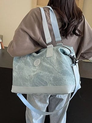 Distressed blue duffle bag with adjustable strap and light grey trim