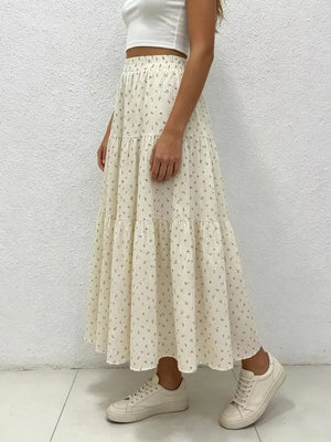 Ruched floral tiered maxi skirt in beige with a ruffled hem, styled with a crop top and sneakers.