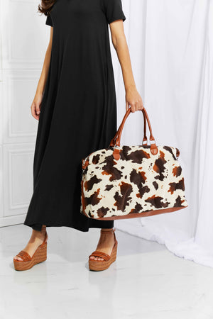 Cowhide print duffel bag with brown leather trim and handles
