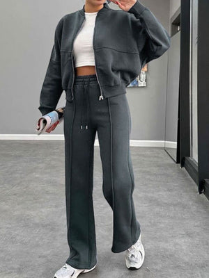 Dark blue bomber jacket and wide-leg tracksuit with drawstring pants and white crop top.
