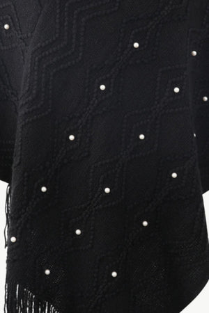 Black knit poncho with geometric pattern and pearl embellishments, featuring fringe detail.