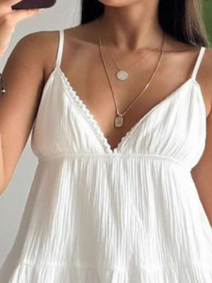 White cotton tiered mini dress with lace trim neckline and spaghetti straps.