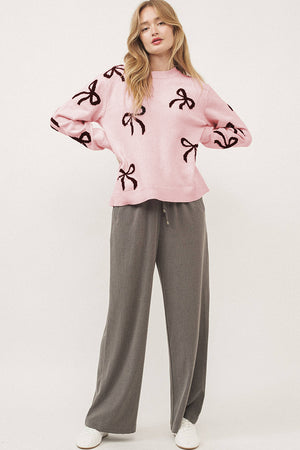 Blush pink knit crewneck sweater with allover dark bow motif pattern.