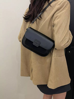 Chic two-tone crossbody bag in black with a textured flap and gold hardware.