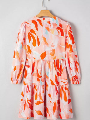 Tiered mini dress with abstract print, long sleeves, and a ruffled hem in pink and orange.