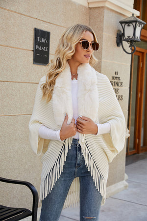 Ivory knit cape with faux fur collar and fringe detail