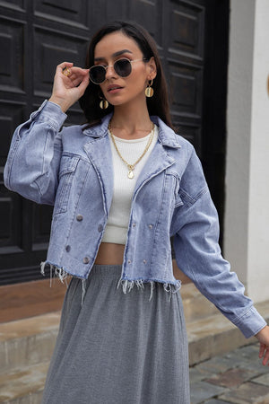 Light denim cropped trucker jacket with raw hem and double button closure.