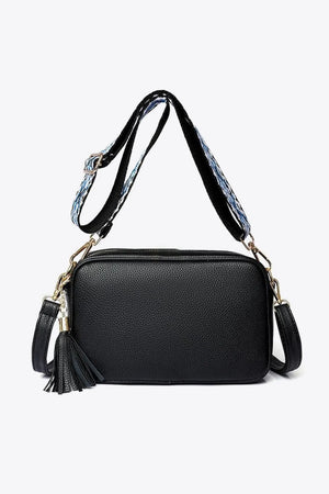 Black textured crossbody bag with tassel detail and patterned strap