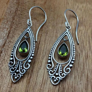 Silver filigree drop earrings with pear-shaped peridot stones and ornate detailing.
