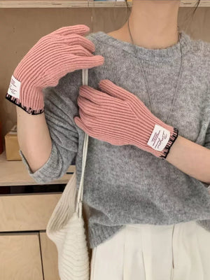 Pink ribbed knit gloves with scalloped cuff detail and white label