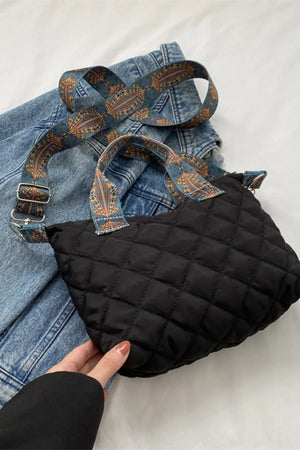 Black quilted satchel with a patterned strap and denim styling.