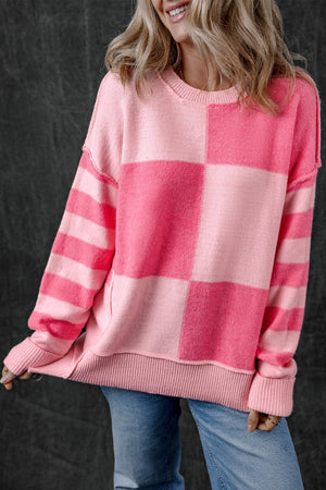 Checkerboard knit crewneck sweater in blush pink with striped sleeves and ribbed trim.