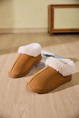 Caramel suede house slippers with plush shearling trim and decorative stitching.