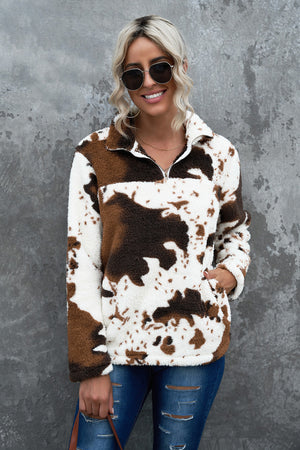 Cowhide sherpa quarter-zip pullover in white with brown cow print, featuring a fuzzy texture and a front pocket.