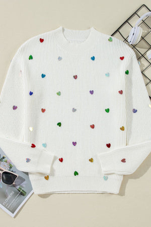 White ribbed knit sweater with colorful heart embellishments.