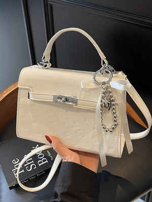 Ivory embossed pu leather mini crossbody bag with dog and heart pattern and charm.