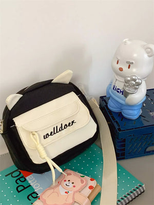Black crossbody bag with white accents and cat ears, "welldoer" text detail.