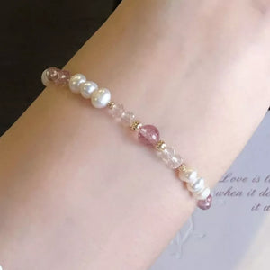 Delicate pearl and crystal bracelet with pink stone accents on a wrist.