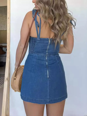 Blue denim mini dress with smocked bodice and tie straps, back zipper detail.
