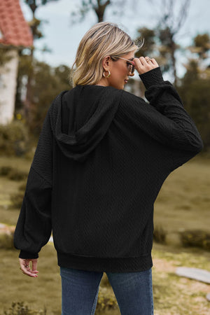 Black cable knit zip-up hoodie with textured fabric and relaxed fit.