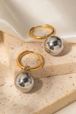 Orbital gold hoop earrings with dangling silver spheres.