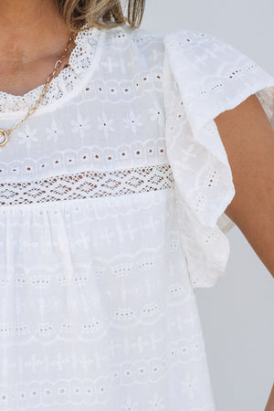 White eyelet blouse with ruffle sleeves and lace inset detail.