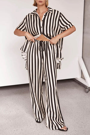Vertical stripe lounge set in white and black with buttoned shirt and drawstring pants.