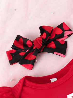Red baby bodysuit with ruffled sleeves and a black headband with red hearts.