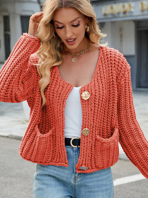 Chunky knit cardigan in orange with gold buttons and patch pockets.