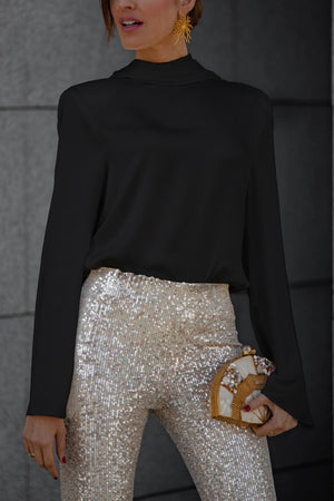 Black silk blouse with high neck and draped back detail, paired with sequin pants.