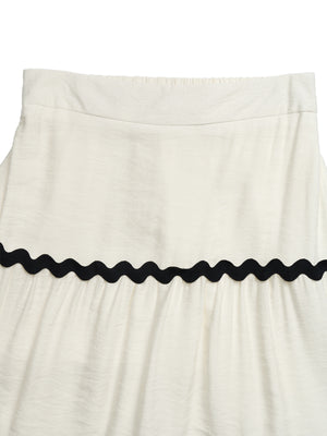 Beige tiered midi skirt with wavy black trim and textured fabric.