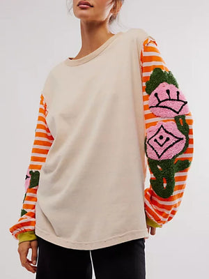Beige long sleeve tee with embroidered floral applique on orange striped sleeves