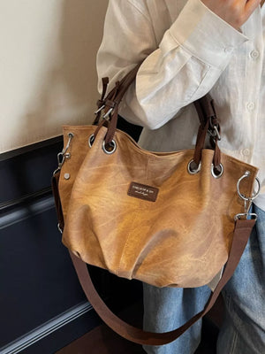 Slouchy crossbody bag in tan faux leather with adjustable strap and silver hardware.