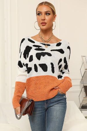 Cow print off-shoulder knit sweater with orange colorblock detail and boat neck.