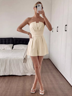 Cream pleated V-neck strapless romper with a cinched waist and short shorts.