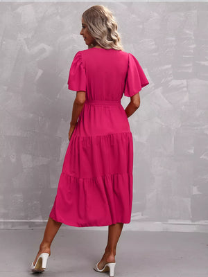 Hot pink tiered midi dress with flutter sleeves and belted waist.