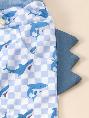 Baby blue checkered shorts with blue shark print and dinosaur tail detail.