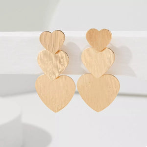 Gold heart-shaped dangle earrings with textured finish