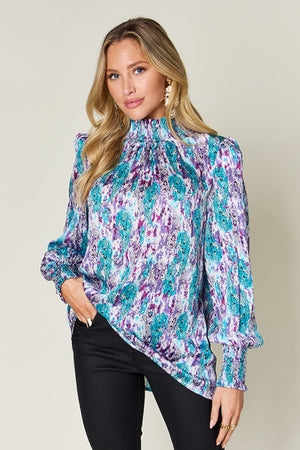 High neck abstract print blouse in red-violet and sky blue with smocked cuffs and collar.