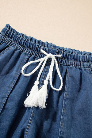 Navy denim drawstring shorts with white tassel tie and frayed hem detail.
