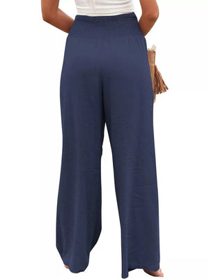 Dark blue smocked maternity pants with wide legs and a comfortable fit.