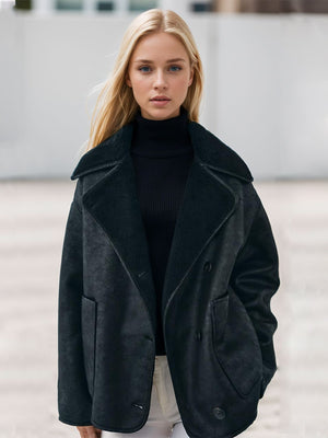 Black aviator jacket with shearling trim and buttoned front, worn over a black turtleneck.