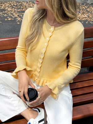 Pastel yellow knit cardigan with ruffled trim and buttons