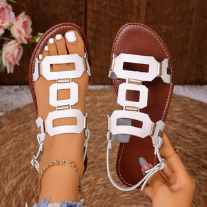 Sleek white cutout open-toe sandals with gold accents and brown soles.