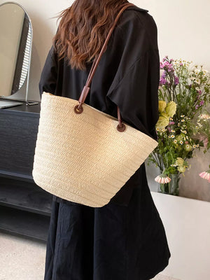 Natural straw woven large shoulder bag in beige with leather straps.